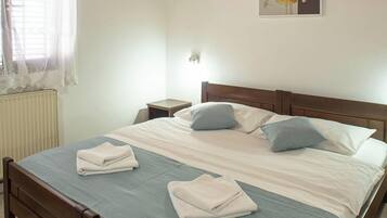 A neatly made bed with a blue bedspread and pillows, a wooden headboard, and a wall-mounted artwork.