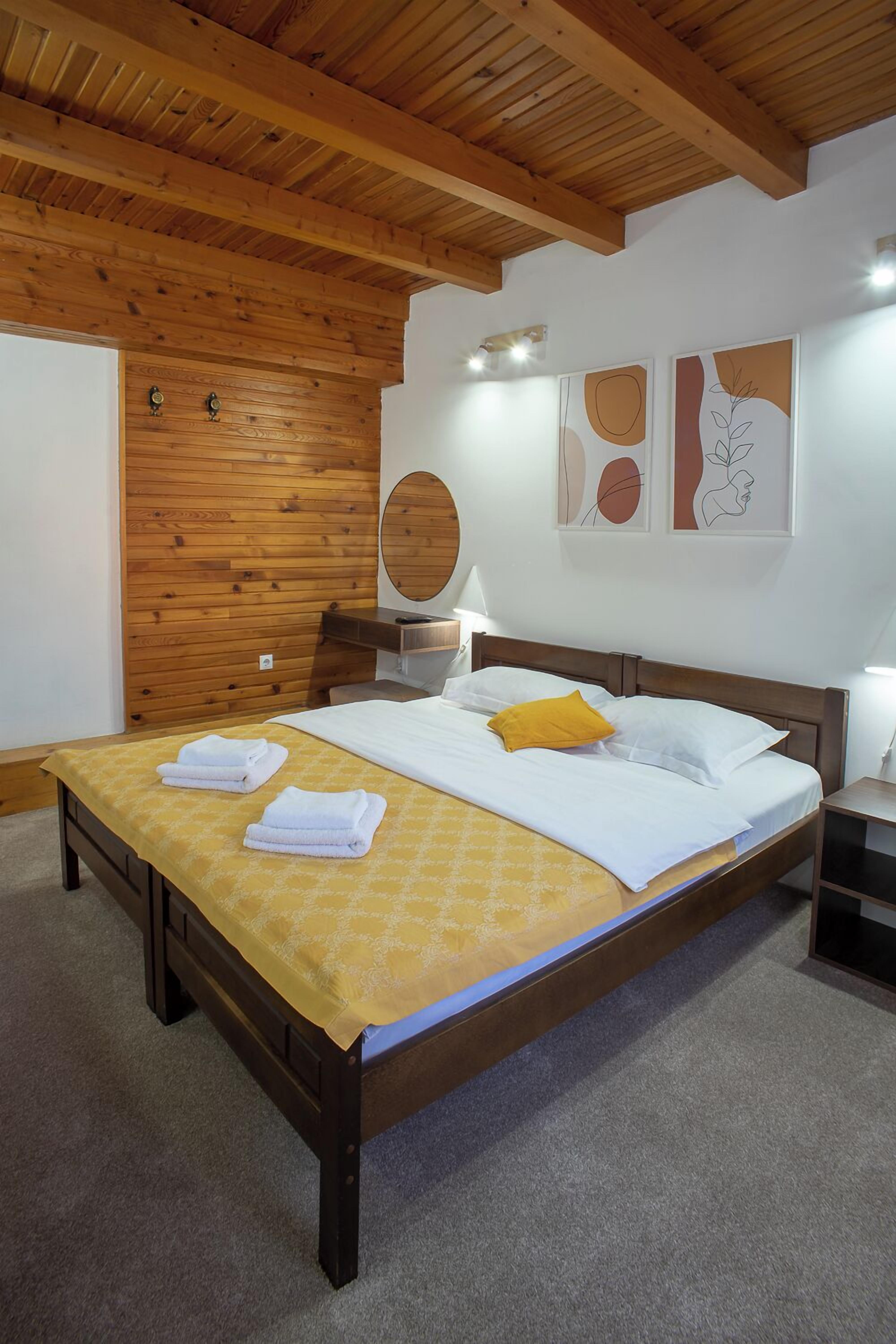 Une chambre à coucher avec un cadre de lit en bois, une couvre-lit jaune et un plafond en bois.
