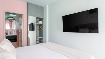 A bedroom with a bed, a wardrobe, a mirror, and a television on the wall.