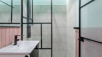 Un baño moderno con cabina de ducha de vidrio, lavamanos blanco y paredes con azulejos.