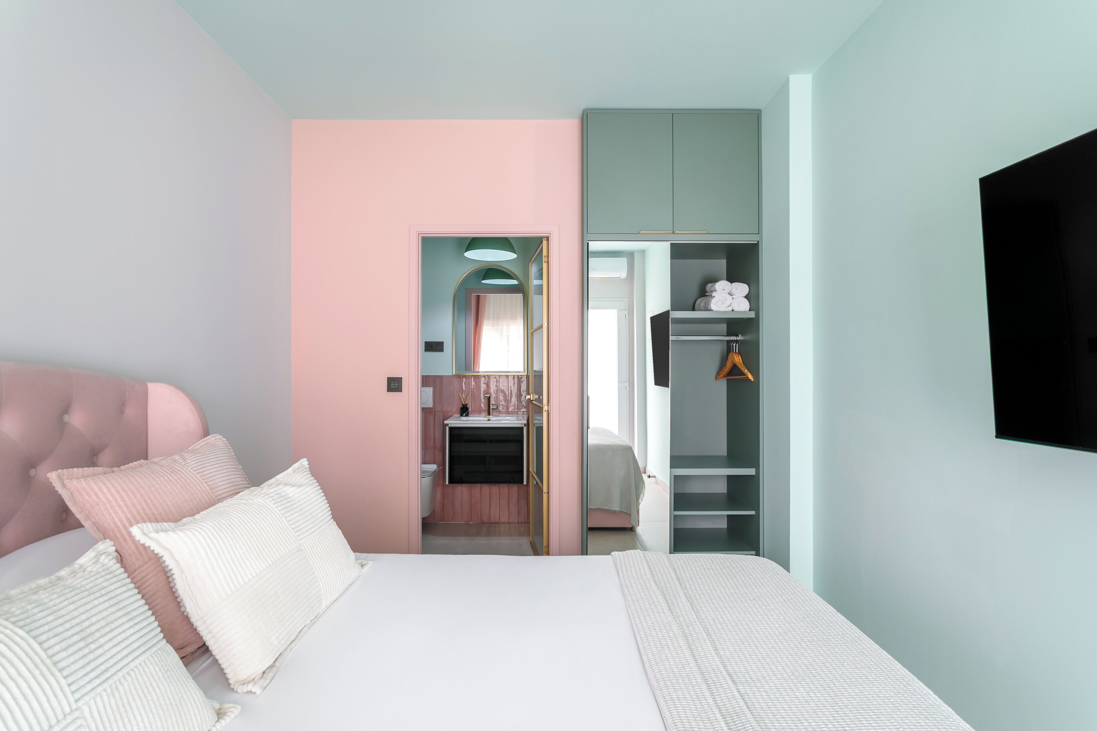 A bedroom with a bed, a wardrobe, and a television.
