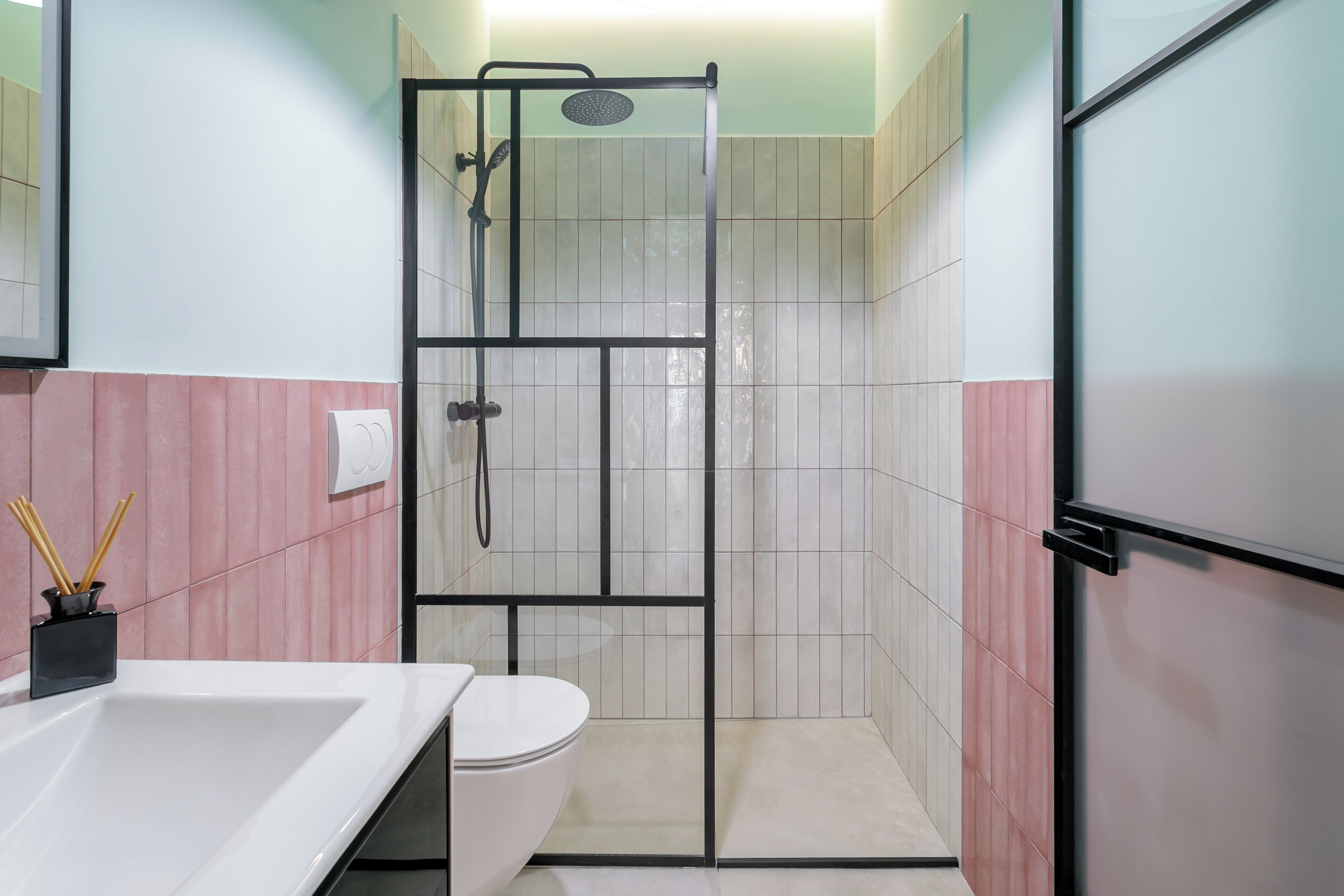 A bathroom with a glass shower enclosure, a white sink, and a toilet.