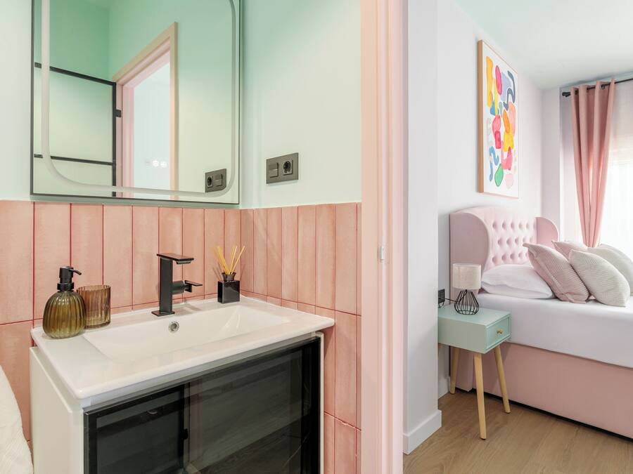 Un dormitorio moderno con una cama grande, una mesita de noche y un espejo sobre el lavamanos.