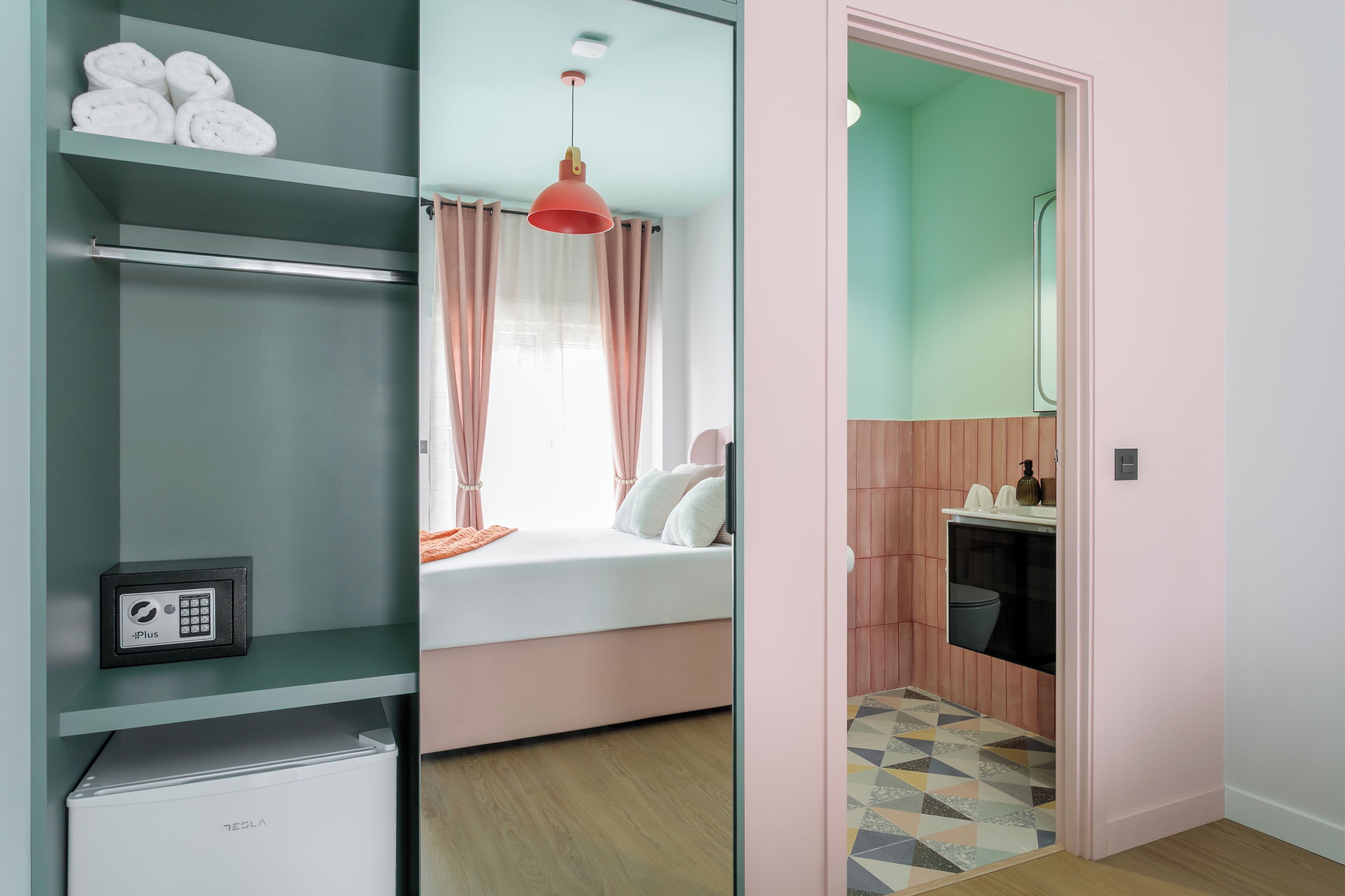 Une chambre moderne comprenant un lit, une armoire, un petit réfrigérateur et une salle de bain avec des toilettes et un lavabo.