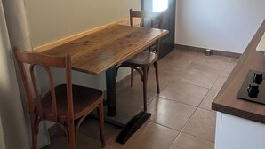 A kitchen with a wooden table and chairs, a built-in shelf, and a door with a window. - Apartment with terrace for 2 people Le nid du phénix 38 in the countryside (Arandon-Passins)