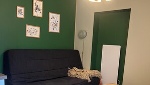 A living room with a black sofa, a wooden coffee table, a yellow ottoman, and green walls. - Apartment with terrace for 2 people Le nid du phénix 38 in the countryside (Arandon-Passins)