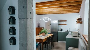 Eine Küche mit Holzbalken, einem Kühlschrank, einer Mikrowelle und einem Esstisch mit Stühlen.