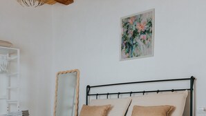 Ein Schlafzimmer mit einem Bett, einer Holzbalkendecke, einem Spiegel und einem Bild an der Wand.
