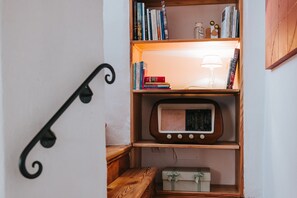 A wooden bookshelf with books, a radio, and a lamp.