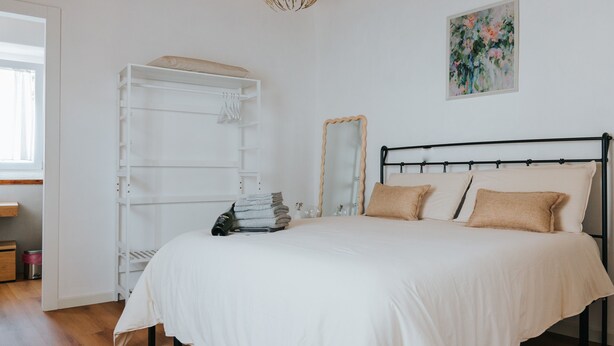 Ein Schlafzimmer mit Bett, Kleiderschrank, Spiegel und einem Bild an der Wand.