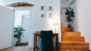 A room with a wooden desk, a green chair, a lamp, a staircase, and a potted plant. - Room 'With Castle View' with Wi-Fi and Air Conditioning (Cison di Valmarino)
