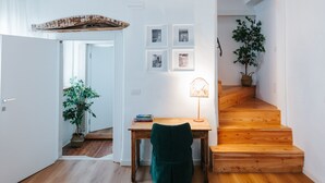 A room with a wooden desk, a chair, a lamp, a staircase, and a potted plant. - Room 'With Castle View' with Wi-Fi and Air Conditioning (Cison di Valmarino)