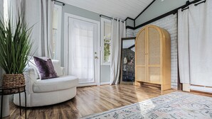 Une pièce avec un canapé blanc, une grande plante en pot, un tapis à motifs, un plancher en bois et un meuble en bois orné d’un motif tissé.
