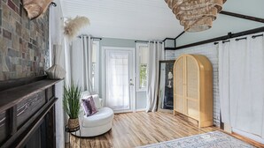 Une pièce avec une cheminée, un fauteuil rond blanc, une tête d’animal suspendue au mur, un meuble en bois et un grand lustre en osier.