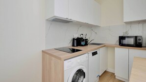 A compact kitchen with a washing machine, a microwave, and a coffee maker on the countertop. - Cosy Apartment - 1bdr-4p - Ivry-sur-seine (Ivry-sur-Seine)