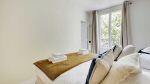 A hotel room with a bed, a window with curtains, and a view of trees outside. - Cosy Apartment - 1bdr-4p - Ivry-sur-seine (Ivry-sur-Seine)