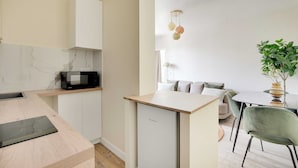 A compact kitchen with a microwave, a small refrigerator, and a dining area with a table and chairs. - Cosy Apartment - 1bdr-4p - Ivry-sur-seine (Ivry-sur-Seine)