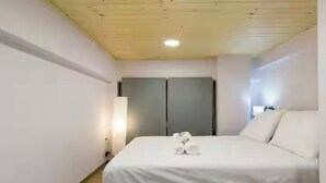 A hotel room with a bed, a wardrobe, and a bedside lamp. - Charming studio in Athens 25sqm (Athina)