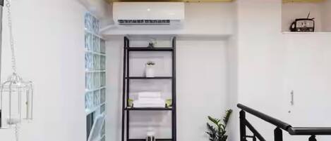 A modern interior with a wooden ceiling, a black metal shelving unit, and a small potted plant.