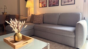 A living room with a grey sofa, a glass coffee table with a vase, and three framed pictures on the wall. - Fatima Experience 50 meters from the Sanctuary of Fátima (Fátima)