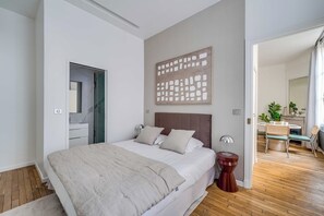 Een slaapkamer met een bed, nachtkastjes, een spiegel en een schilderij aan de muur.