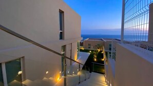 A modern building with a staircase leading to a balcony overlooking a body of water.