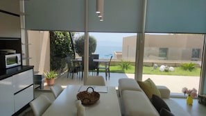 Una sala moderna con comedor, ventanas amplias y vista al mar.