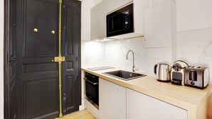 A kitchen with a black door, a microwave, a toaster, a kettle, and a sink. - Cosy Studio - 2P - Place de la Concorde - Saint-honore (Paris)