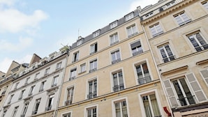 A multi-story building with uniform windows and balconies, featuring a storefront with a sign. - Cosy Studio - 2P - Place de la Concorde - Saint-honore (Paris)
