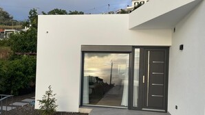 Un edificio moderno con un amplio ventanal y un pequeño jardín con piedras para caminar.