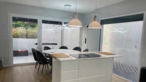 Una cocina moderna con una isla central, iluminación colgante y vistas al exterior.