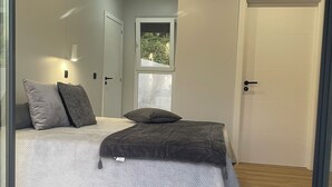 Un dormitorio moderno con cama, almohadas, una ventana y una puerta.
