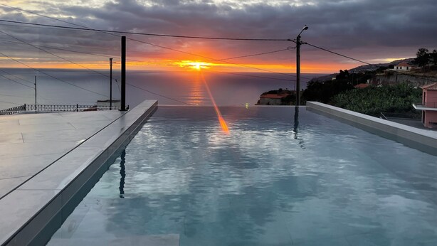 Una piscina con vista al atardecer sobre el mar.