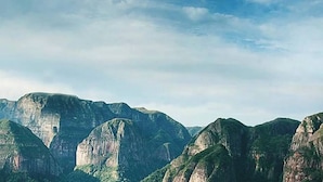 A mountainous landscape with rugged peaks and lush greenery. - Refugio los Volcanes (Cuevas)