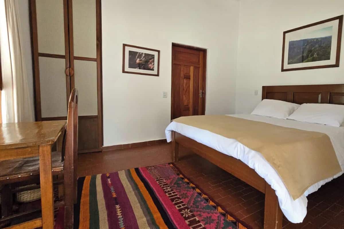 A bedroom with a bed, a wooden door, a chair, and a rug.