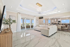 A spacious living area with a large sofa, a flat-screen TV, and a dining area with chairs and a table. - Pool Table * Private pool * Sleeps 16 (Oranjestad)