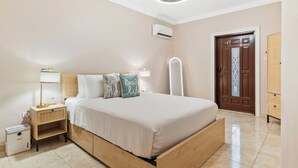 Une chambre à coucher comprenant un lit, une table de chevet, une lampe et un appareil de climatisation.