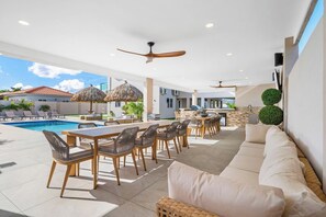 An outdoor pool area with lounge chairs and a dining table.