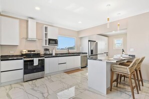 A modern kitchen with a central island, stainless steel appliances, and a view of the outdoors.