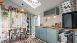 A modern kitchen with a herringbone floor pattern, light blue cabinets, a stainless steel oven, and a skylight above the dining area.