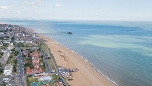 An aerial view of a coastal town with a beach, a pier, and residential buildings.