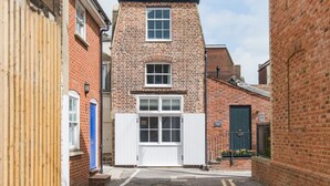A narrow street with a brick building featuring a white door and windows.