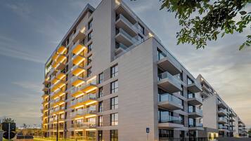 Un moderno edificio residencial de varios pisos con balcones, ventanas amplias y una fachada bien iluminada.