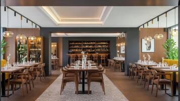 A modern dining area with multiple tables and chairs, a central bar, and a well-stocked liquor cabinet.
