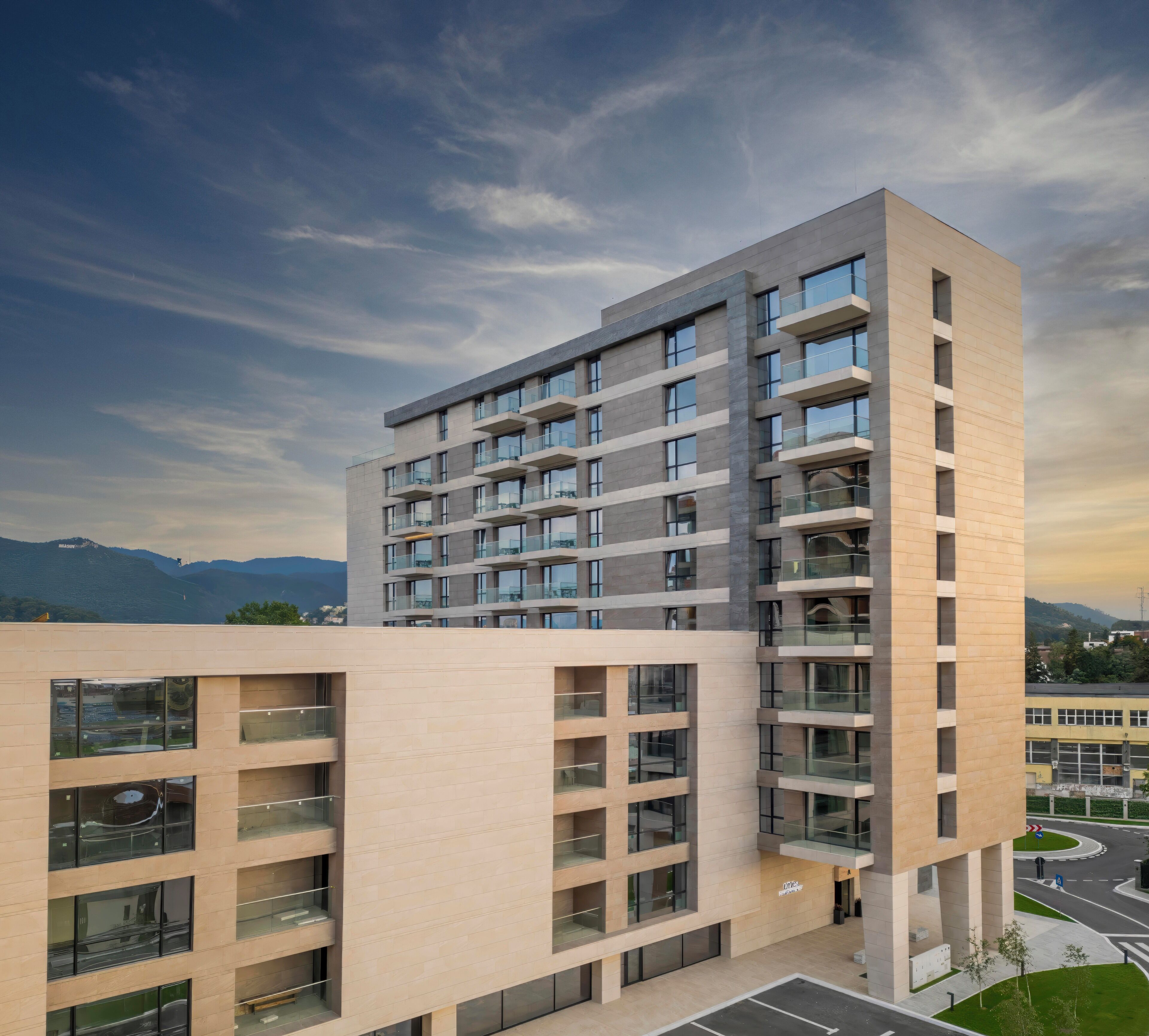 Un edificio de varios pisos con un diseño arquitectónico moderno, que combina vidrio y concreto.