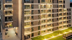 A modern hotel building with multiple balconies, a well-lit entrance, and a landscaped courtyard. - ONE66 (Brașov)