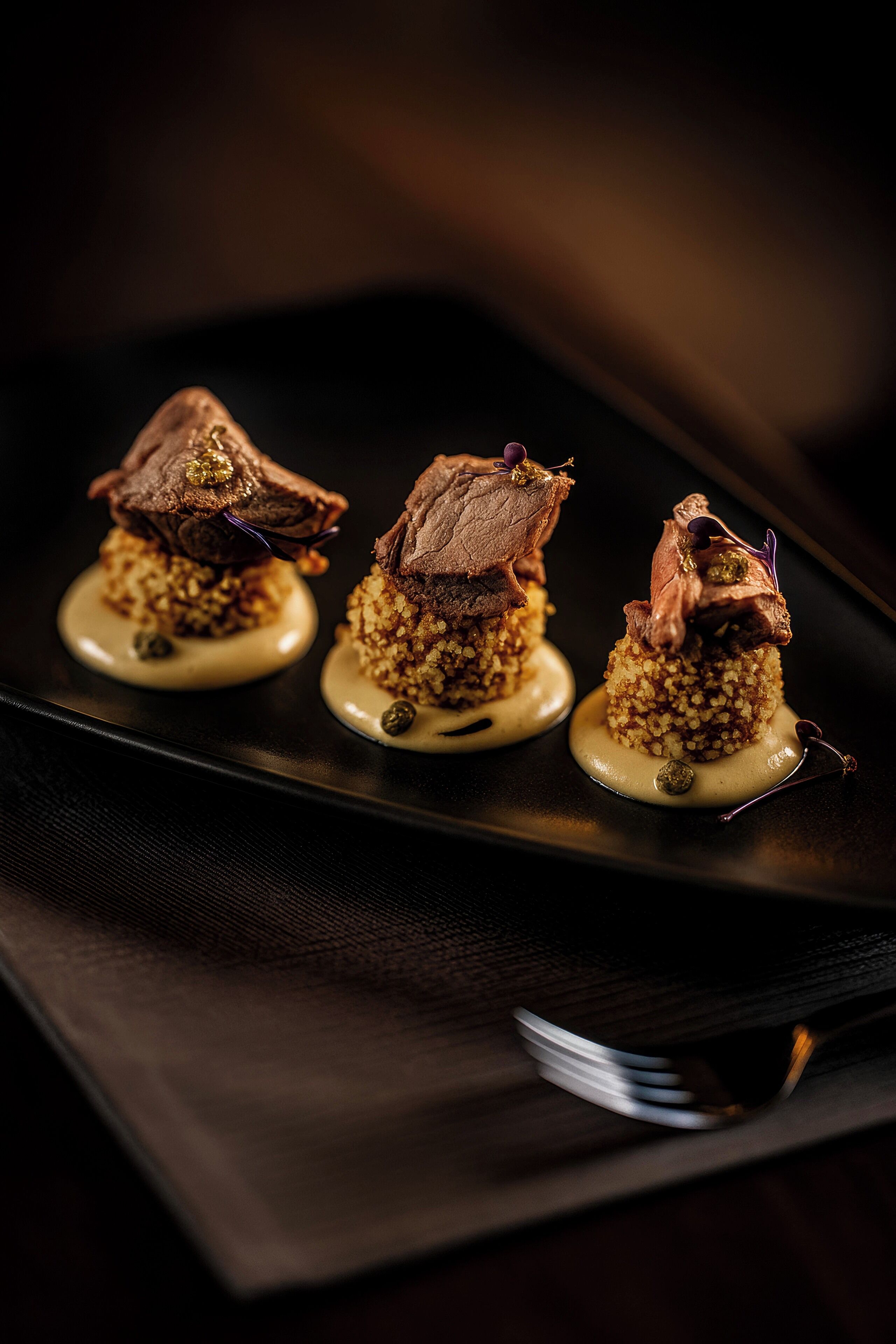 Tres platos sobre un plato negro con un tenedor al lado.