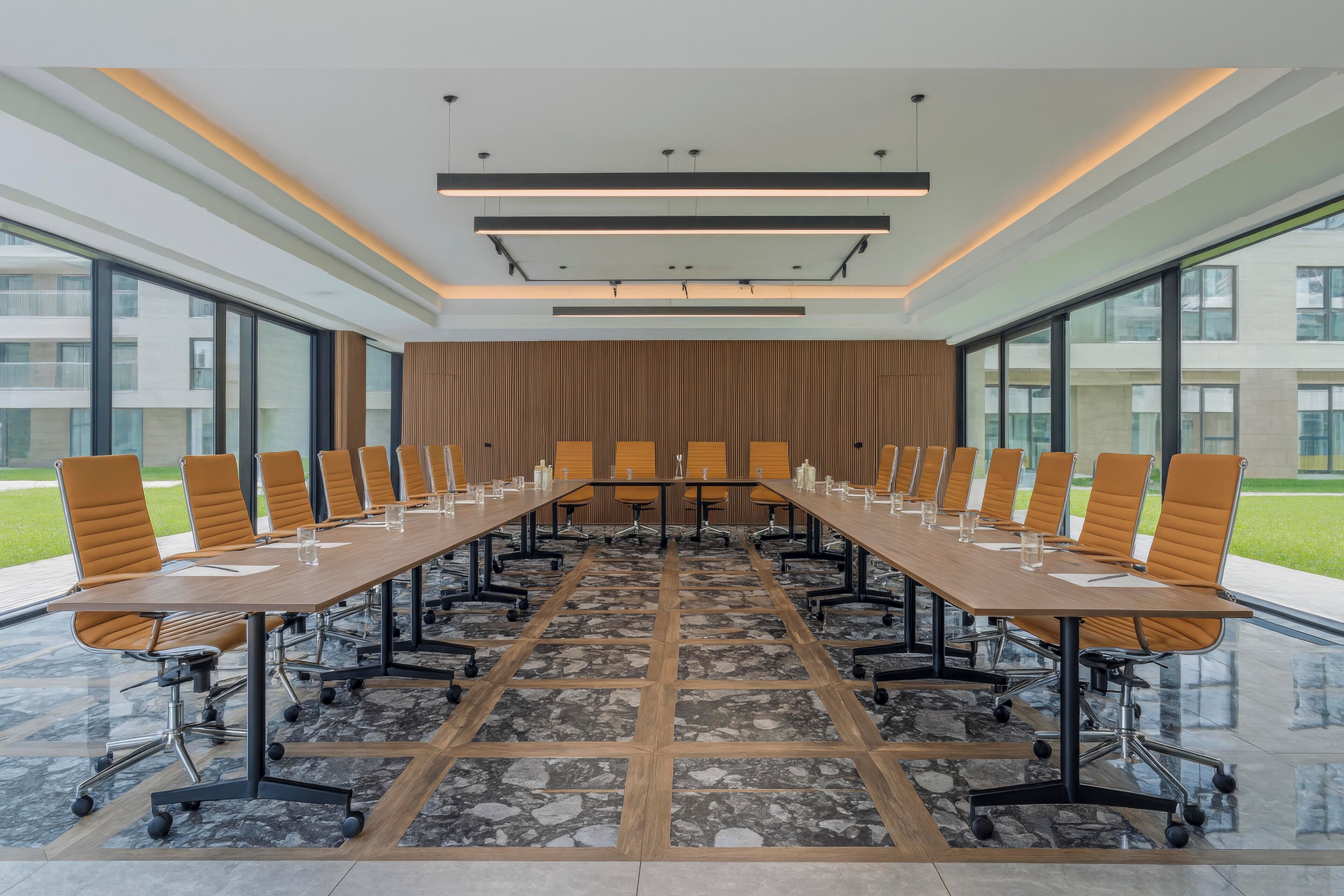 Een vergaderzaal met een lange tafel, stoelen en een modern plafondontwerp.