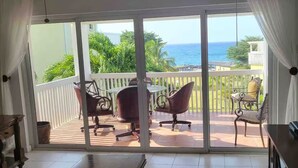 A room with a sliding glass door leading to a balcony with a view of the ocean.
