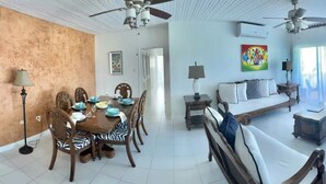 A spacious living area with a dining table set, a sofa, a TV, and a ceiling fan.